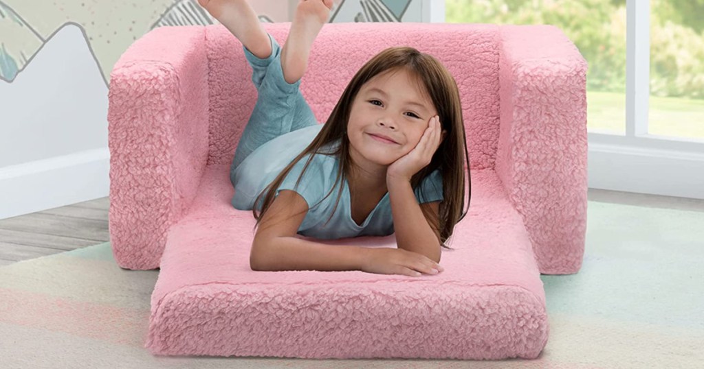 little girl laying down and smiling in pink sherpa kids lounge chair
