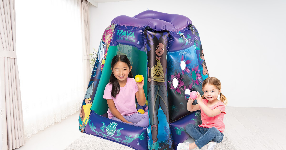 two girls playing inside inflatable ball pit in living room