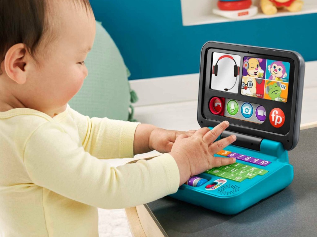 baby playing with toy laptop on table