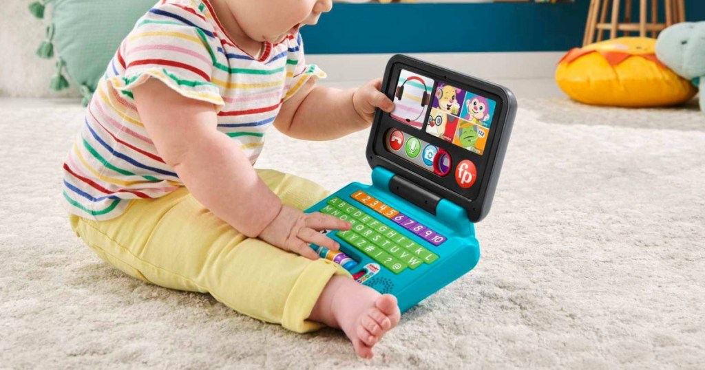 baby playing with toy laptop on carpet