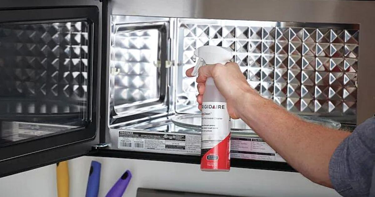 man using Frigidaire Ready Clean Degreasing Oven & Microwave Cleaner on microwave