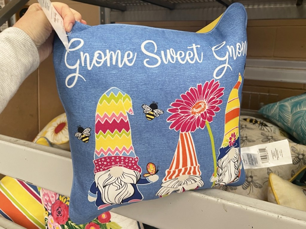 holding up a pillow that says gnome sweet gnome