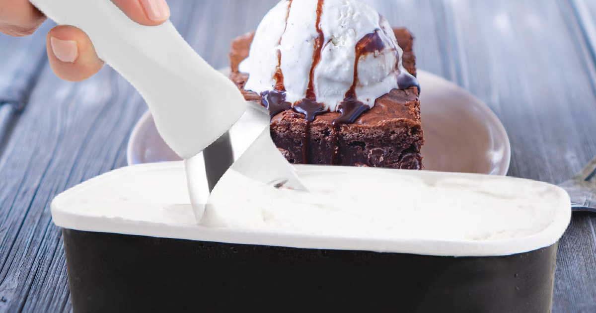 woman's handing scooping out vanilla ice cream and brownie a la mode on table