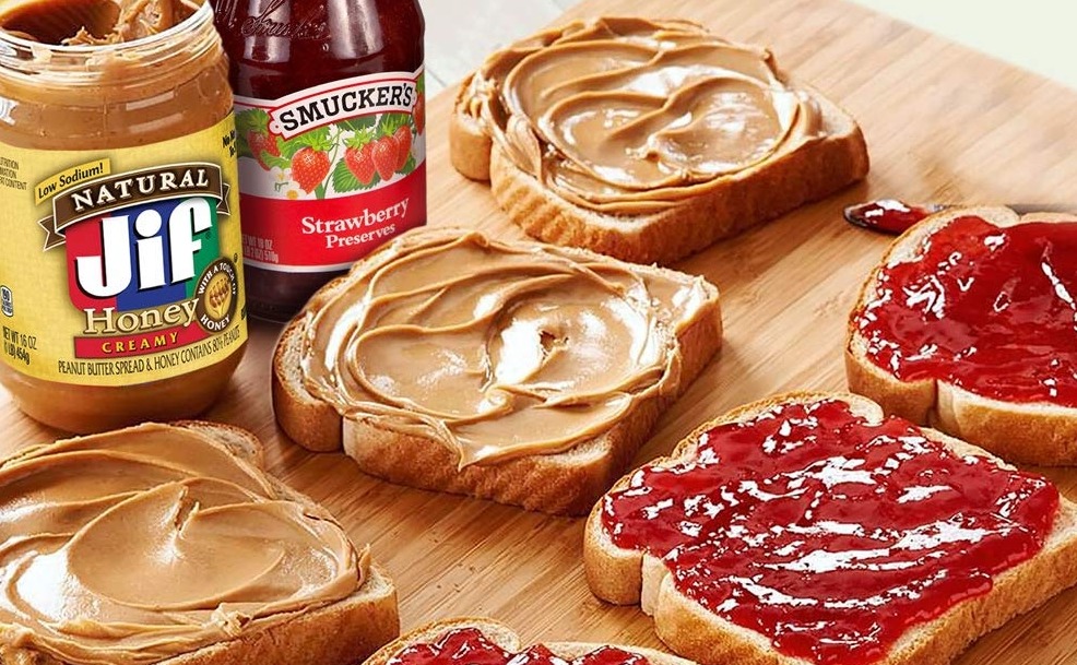 PB&J sandwiches next to container of peanut butter and jelly