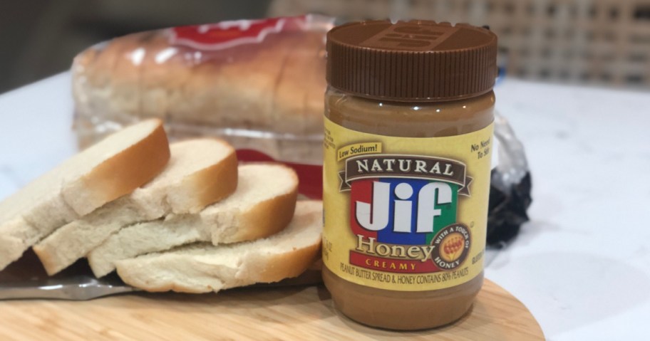 JIF Honey Peanut Butter container on cutting board next to slices of bread