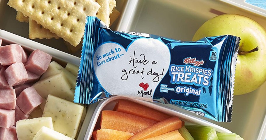 Kellogg's brand Rice Krispies treat sitting on top of bento box with crackers, apple, carrots and cheese
