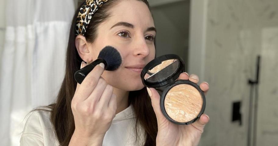 woman putting foundation onto cheeks with brush
