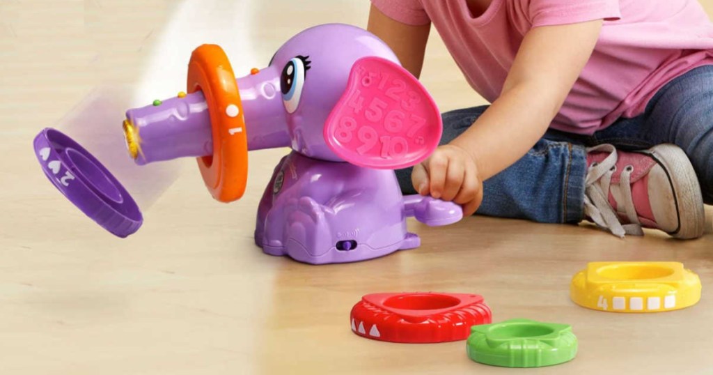 girl playing with purple elephant toy on floor