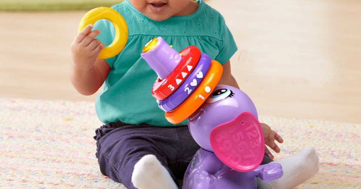 baby girl playing with purple elephant toy on floor