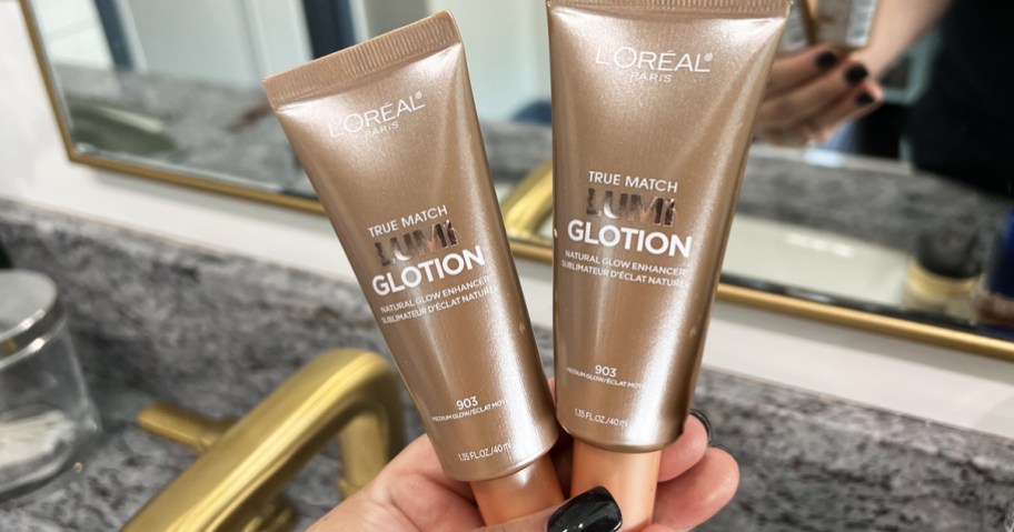 hand holding up two tubes of L'Oreal Lumi Glotion