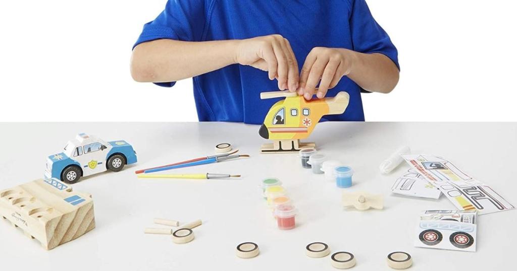 boy playing with Melissa & Doug Rescue Vehicles Wooden Craft Kit