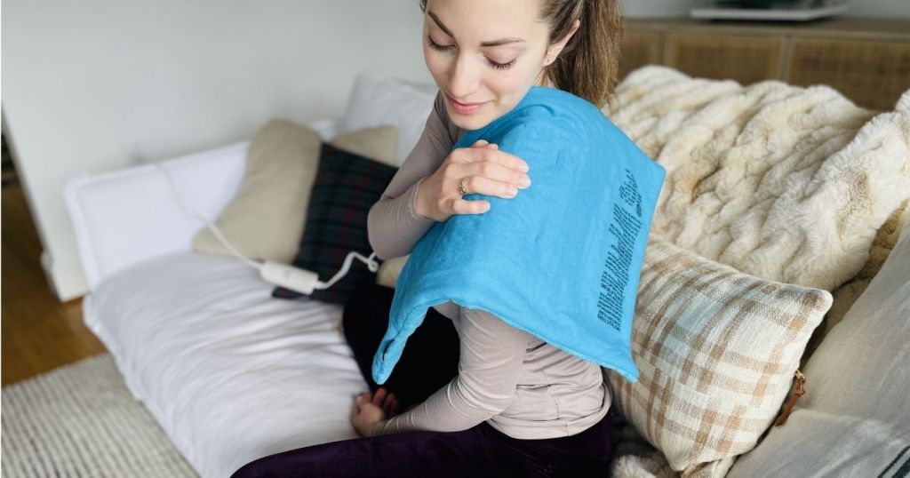 woman using blue heating pad on her shoulder