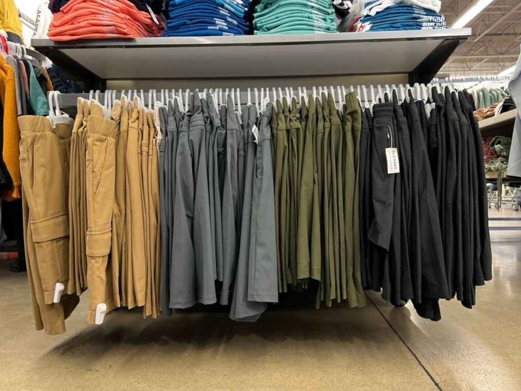 tan, gray, green, and black mens shorts hanging on rack in store