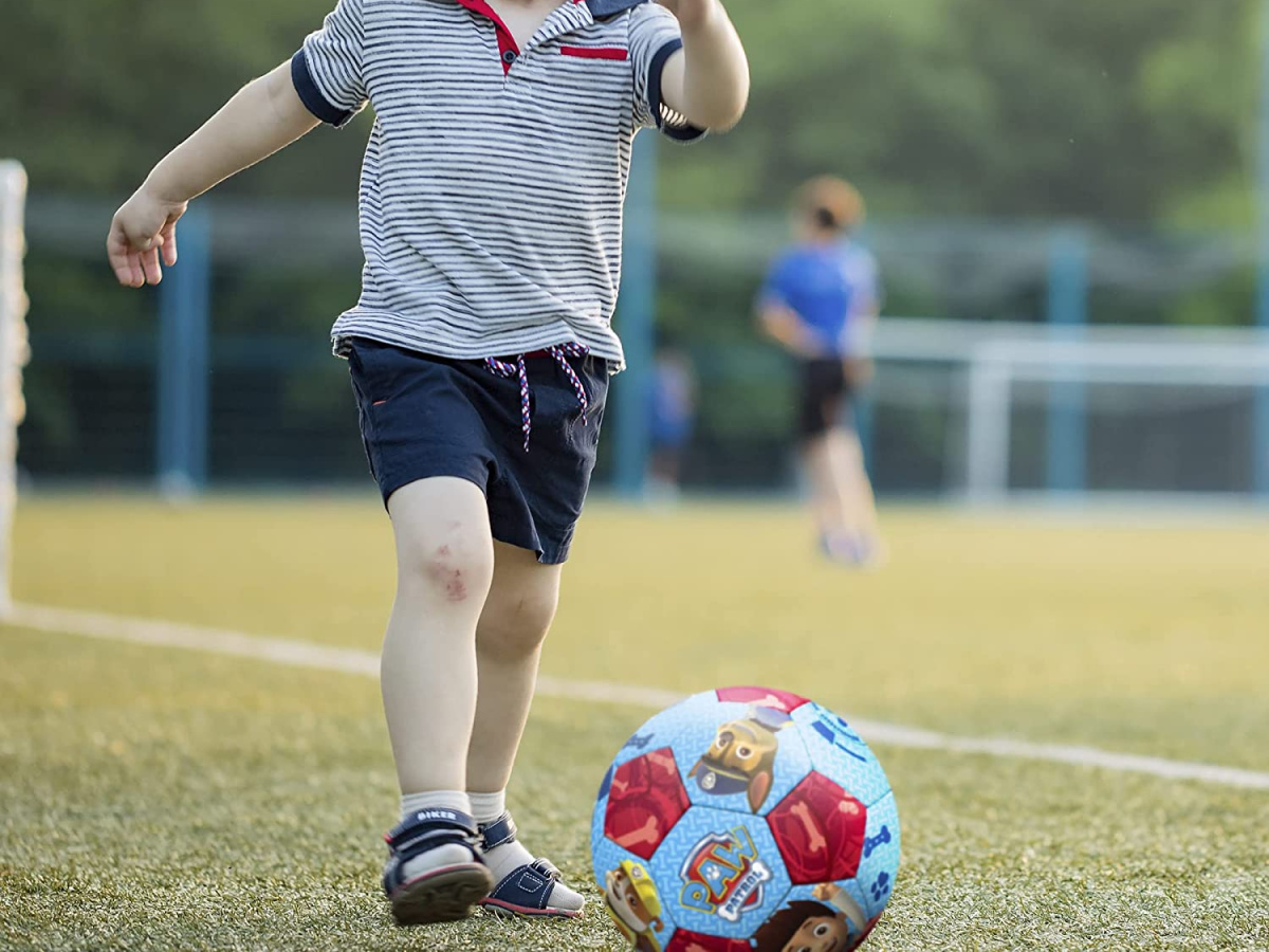 boy kicking soccer ball on field