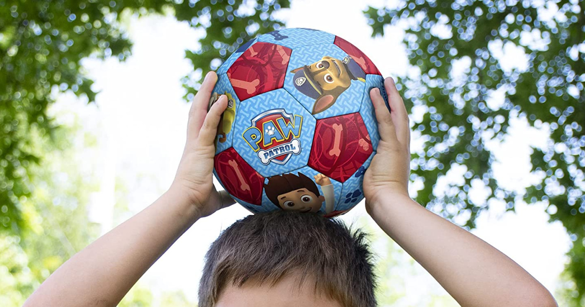 boy holding soccer ball above head