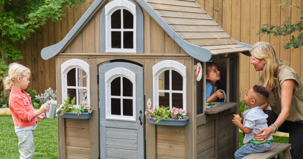 Mother and children playing in outdoor playhouse