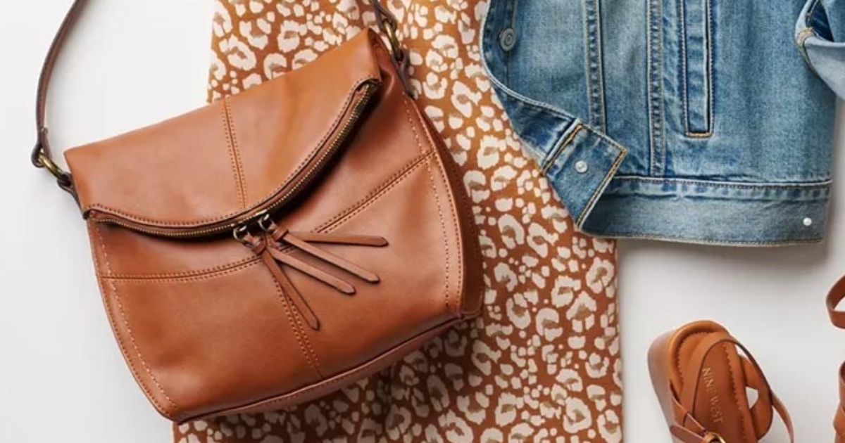 brown leather crossbody purse laying on a flowered dress and jean jacket