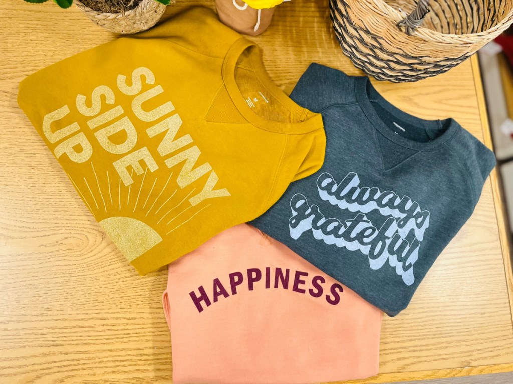 three women's sweatshirts in different designs on table in store