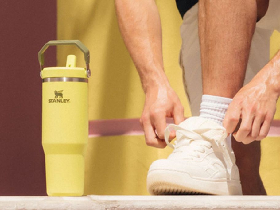Man tying his shoe next to a Stanley IceFlow 2.0 Flip Straw 30oz Tumbler in Prickly Pear color