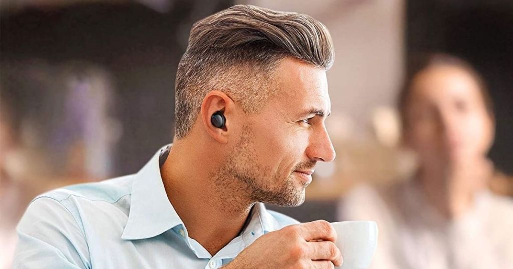 man drinking coffee wearing black Taotronics earbud
