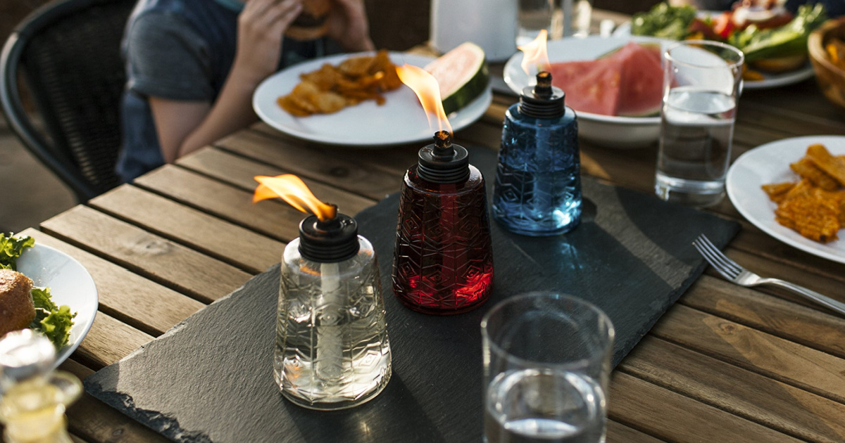 wooden slat table with slate running and mini tiki torches surrounded by food and people eating