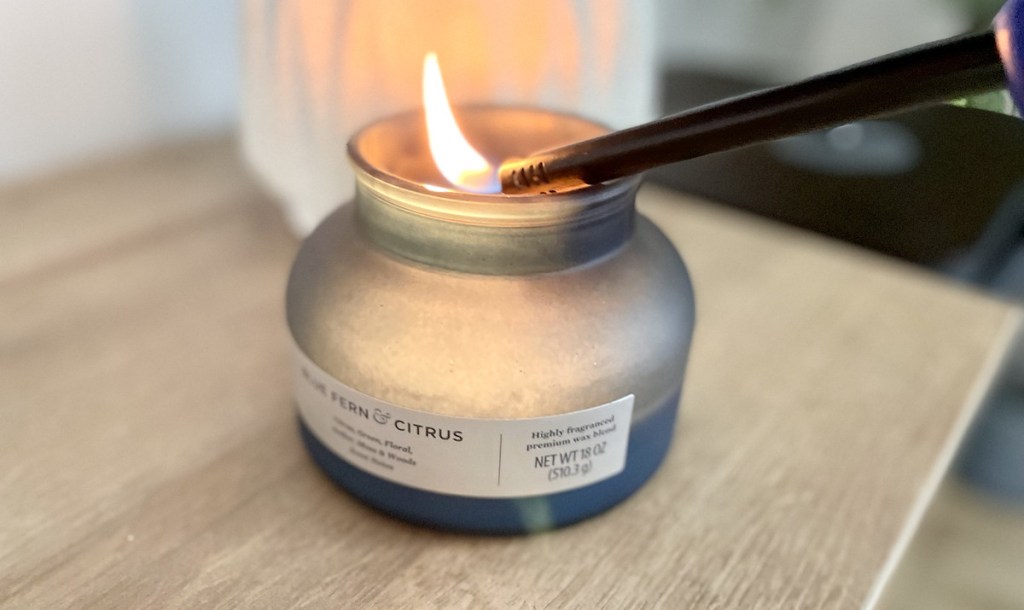 lighter hovering over blue glass jar candle