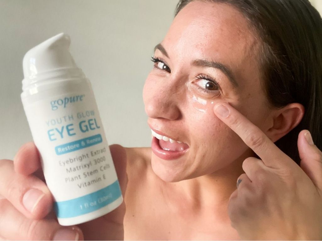 woman holding up Go Pure Eye Gel and putting gel on face with other hand