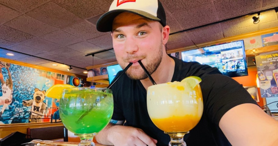 man drinking from two cocktails from Applebees for their St. Patrick's Day deals