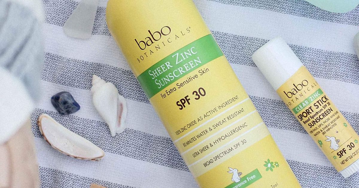 babo botanicals sunscreen spray and stick on towel with seashells