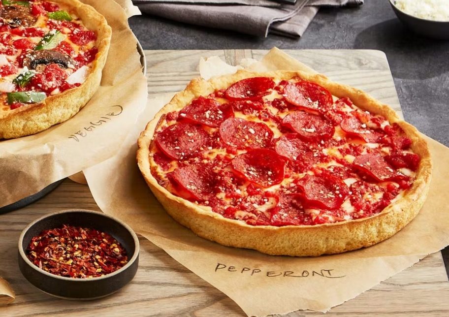 two deep dish pizzas on a wooden cutting board
