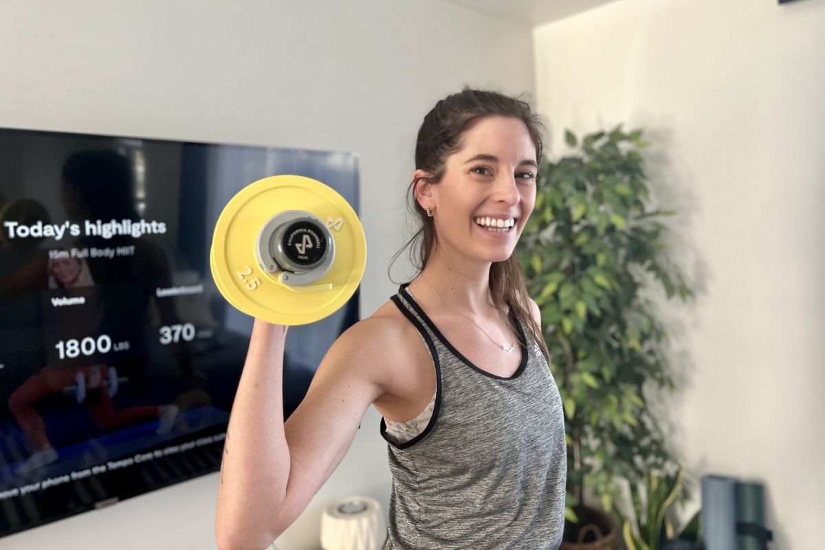 woman holding a dumbbell in front of the television