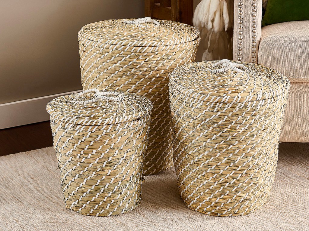 three seagrass baskets with lids sitting next to couch