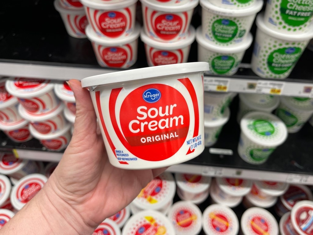 holding a tub of Kroger sour cream