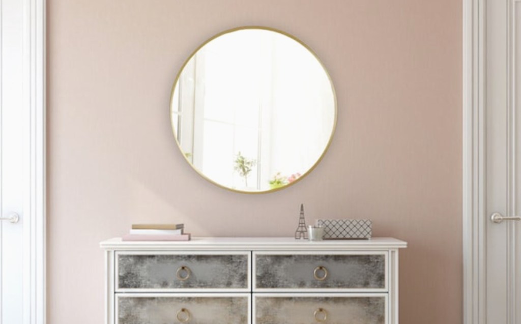 gold round mirror hanging on pink wall