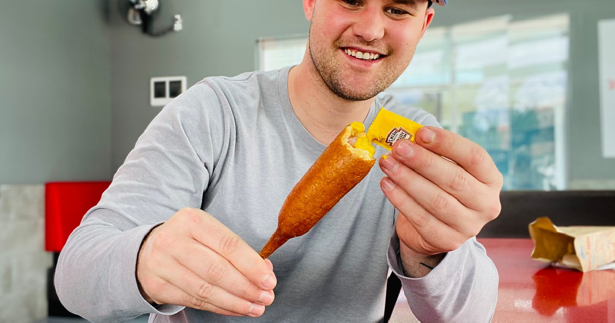man holding sonic drive in corn dog with mustard