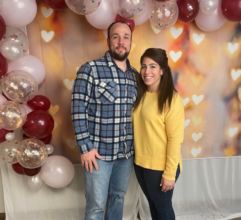man and woman posing in front of heat backdrop and balloon arch