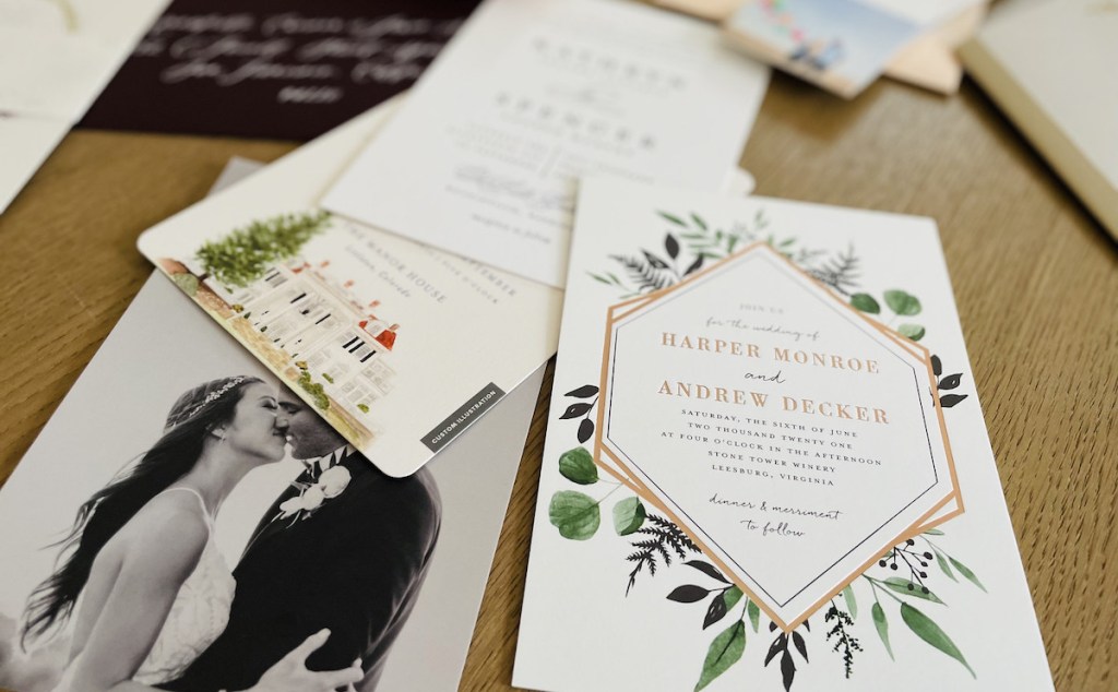 various styles of wedding invitations laying out on wood table