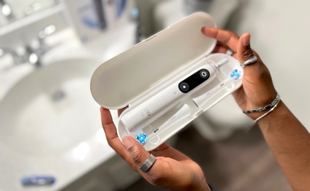 hands holding white travel case with toothbrush inside