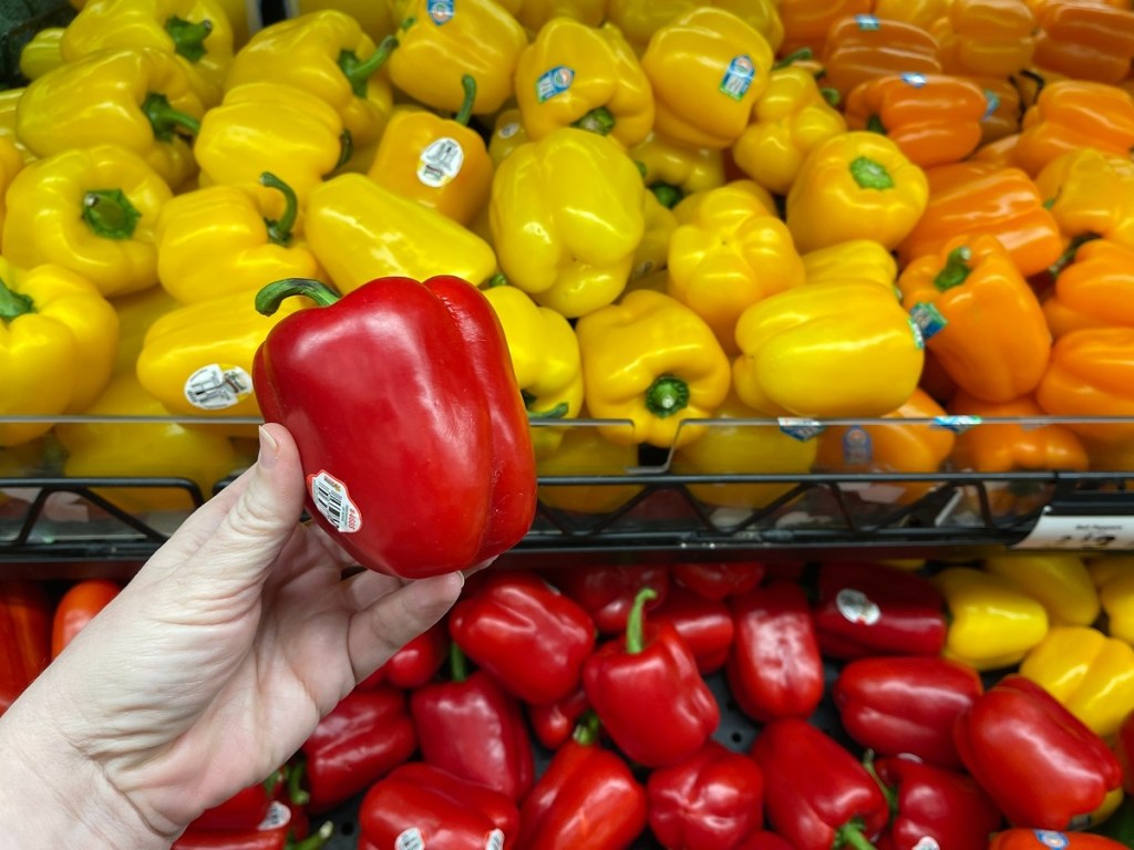 holding a red bell pepper at the grocery store