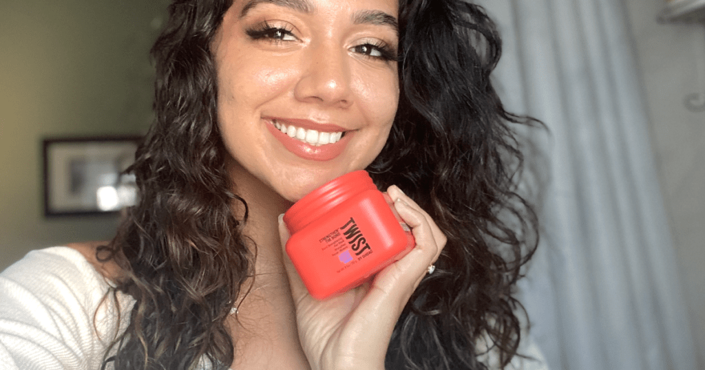 woman smiling and holding twist curly hair product 