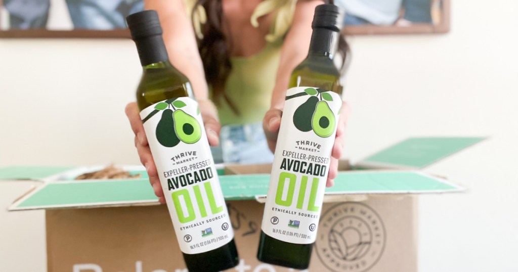 woman holding two avocado oil bottles