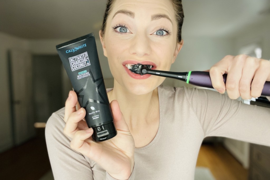 woman brushing teeth w/ charcoal toothpaste