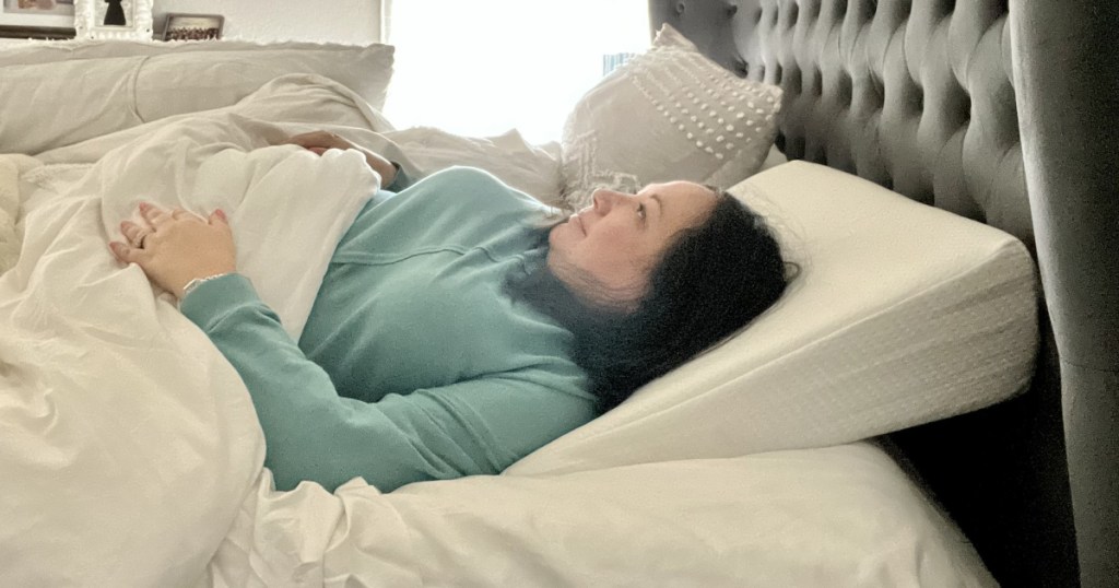 woman laying on wedge pillow in bed