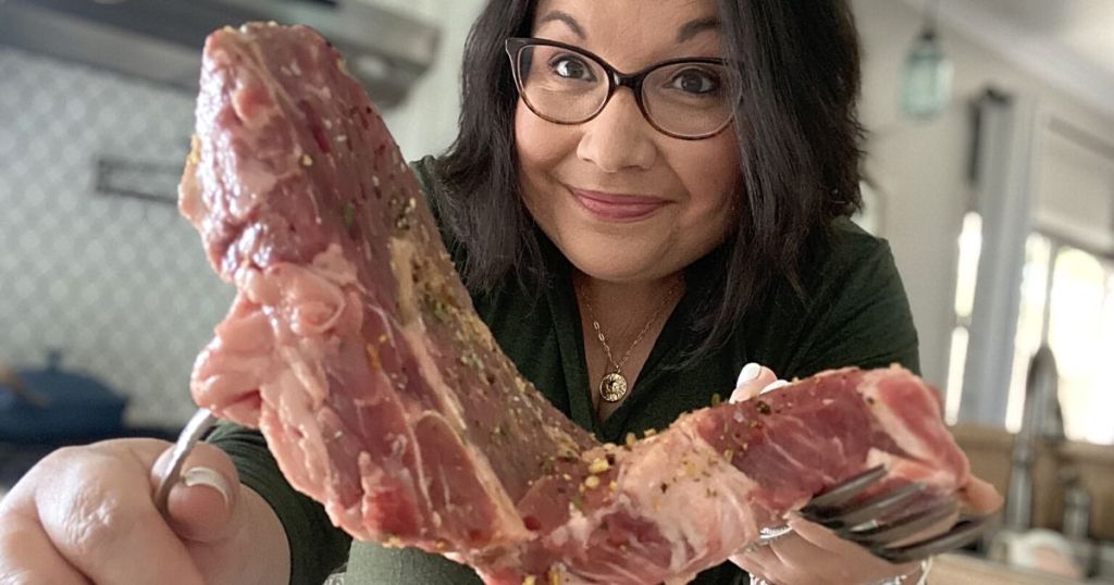 woman holding up raw steak