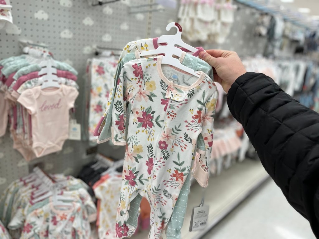 hand holding baby girl bodysuits in store