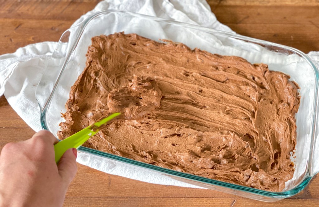 spreading brownie batter in a baking dish