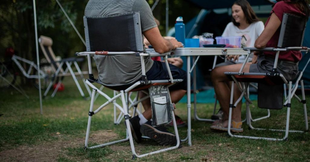 Man sitting in a camping chair at a table with other people