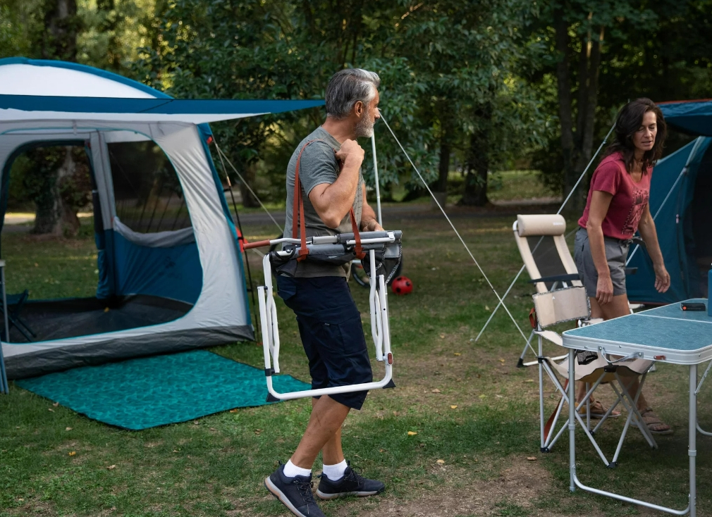 Man carrying a Folding Director's Chair at a campsite
