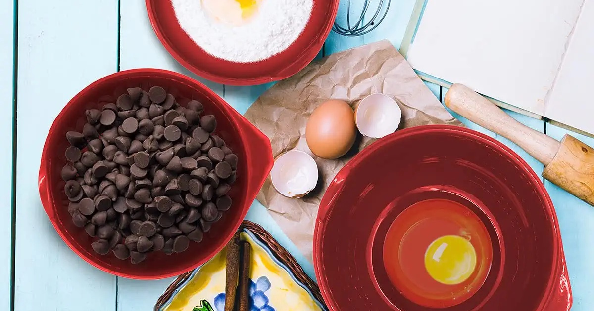 red Glad Mixing Bowls set with ingredients nestled around cracked egg shells, kitchen utensils, and more