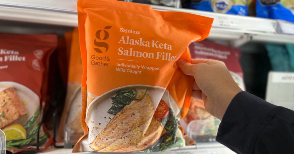 hand holding orange package of frozen salmon 